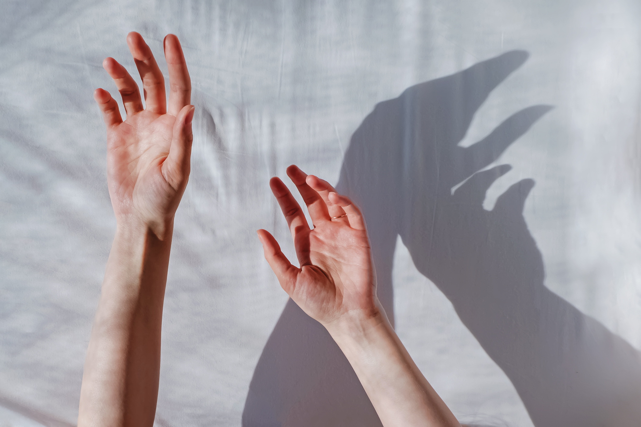 Woman's hand reaching out on white cloth background.